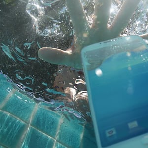Hand reaching for phone dropped in pool 