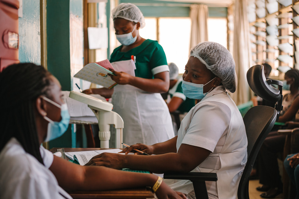 Nurses speak with a patient in a clinical setting as part of the Global Fund’s COVID-19 Response.