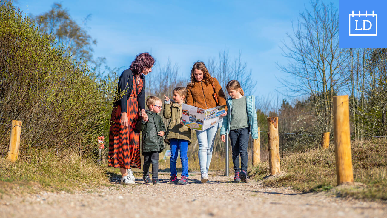 Gezin wandelt door de duinen met kaart