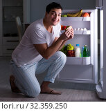 Man at the fridge eating at night. Стоковое фото, фотограф Elnur / Фотобанк Лори