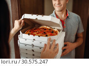 Delivery man shows pizza to customer at the door. Стоковое фото, фотограф Tryapitsyn Sergiy / Фотобанк Лори