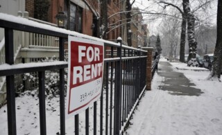 For rent sign on front fence of house in upscale urban neighborhood. The house is for rent during the depths of the winter season