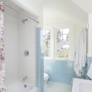 A blue tiled bathroom with a flower shower curtain
