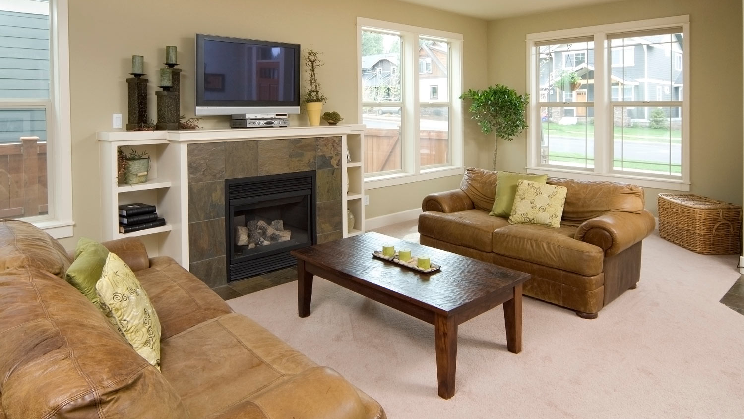 A living room with a fireplace insert and two leather brown sofas