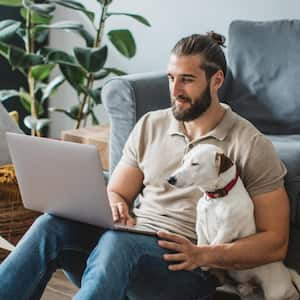 A man next to his pet using laptop