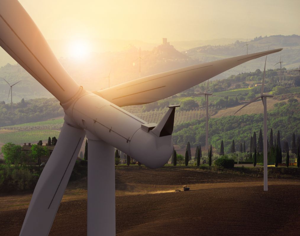 Photo of wind turbines in front of a golden sunset.