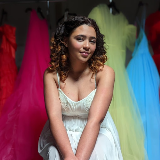 A Real Tone portrait of a woman sitting in front of colorful dresses