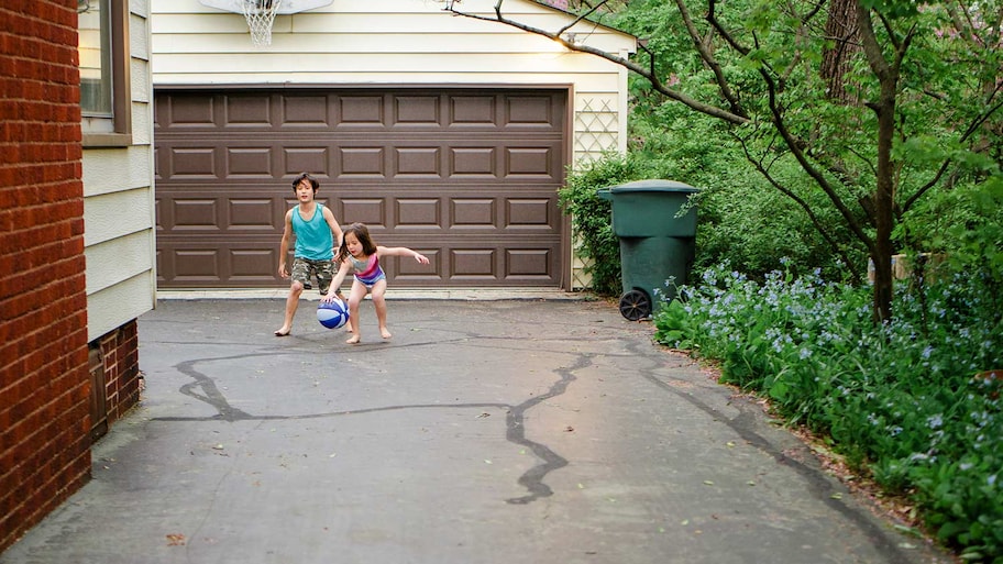 Kids play ball on asphalt drive