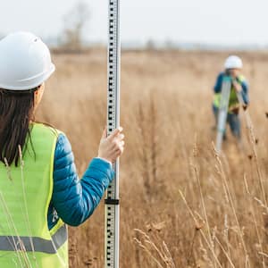 surveyors with survey ruler and digital level in field