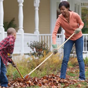 Mother and son rake leaves in front yard