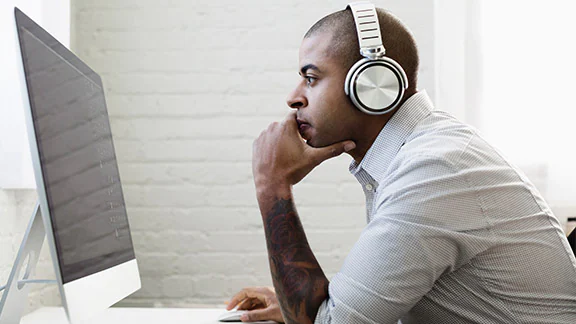 Person wearing headphones looking at a computer monitor