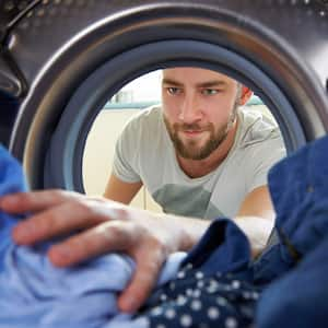 man reaching inside the washing machine. 