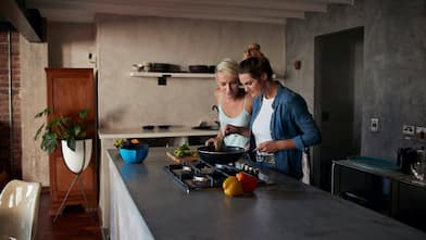 Two young women cooking on a kitchen island