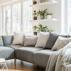 A grey corner couch with pillows and blankets