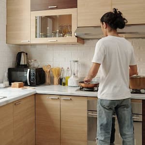 Young man in front of the stove cooking a meal