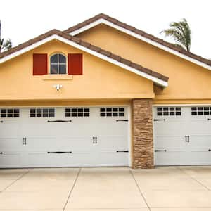 forward view of yellow and brick house with double and single garage and concrete driveway