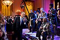 Color photo of Barak Obama singing into a microphone with B.B. King and other musicians and guests.