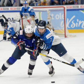 Dos jugadoras de hockey sobre hielo luchan por el puck.