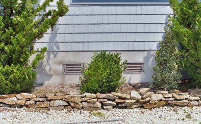 SmartVent flood vents installed on a home with bushes and rocks