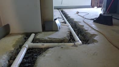 Pipe being installed in basement floor.