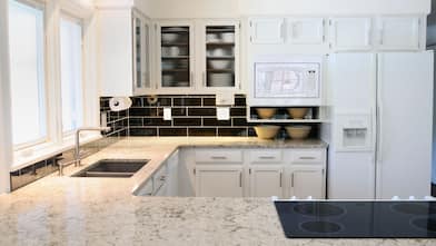 A traditional kitchen with a granite countertop and white cabinets