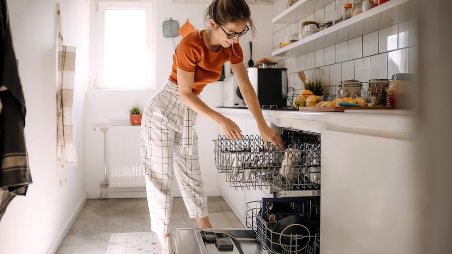 A woman putting dishes in dishwashing machine