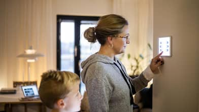 Mother using digital tablet mounted on wall at smart home