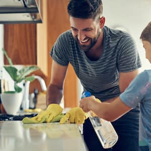 A father and his son sanitize a surface in their kitchen