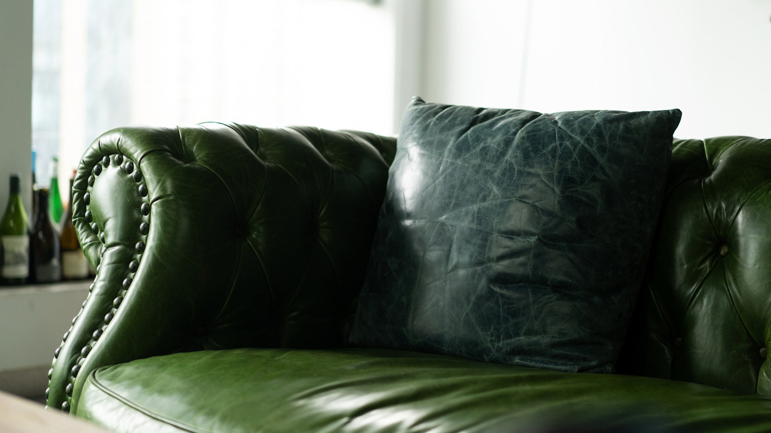 A dark green faux leather sofa