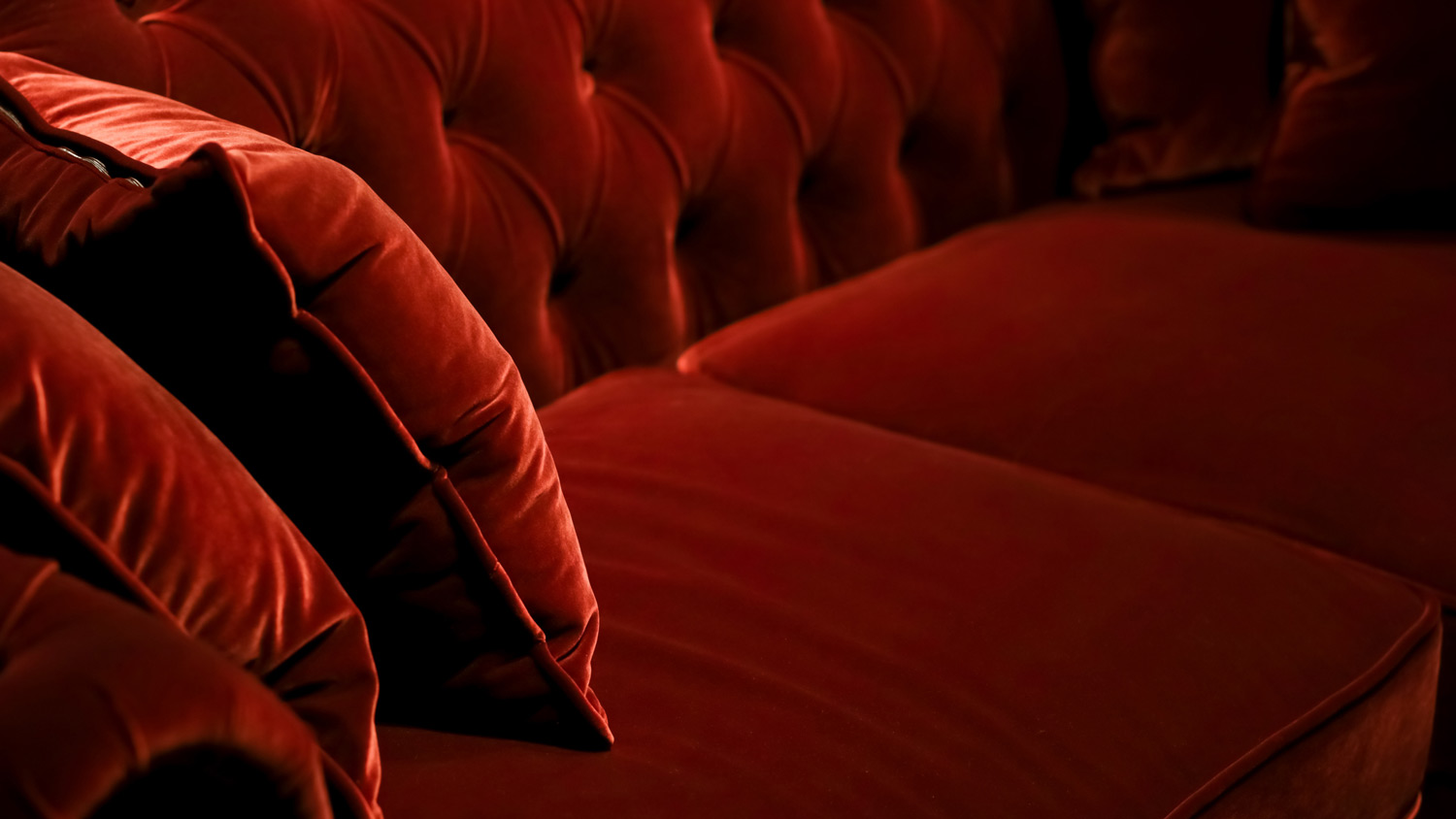 A dark red velvet sofa and its cushions