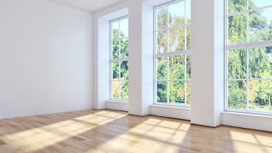 three sunny windows of an empty room overlooking trees