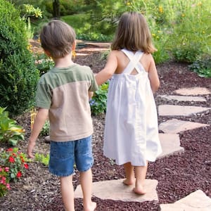 two children walking through backyard landscaping 