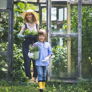  A woman and a young girl harvesting plants from a greenhouse