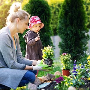Mother and daughter planting flowers outside
