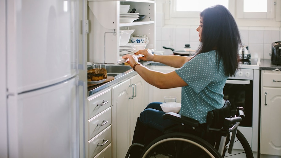 A young woman opening a kitchen cabinet