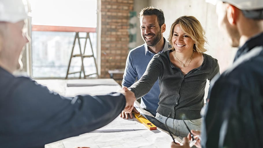 Couple shaking hands with construction workers