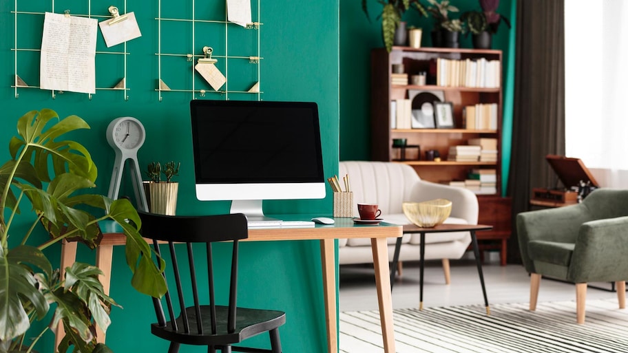 A desk area in a house with the walls painted in emerald green