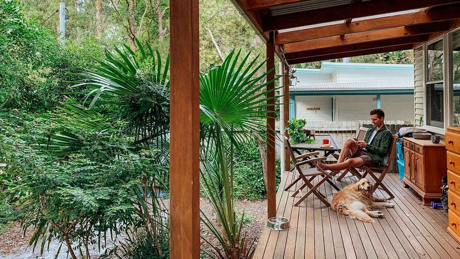 Young man and his dog sitting on a house deck