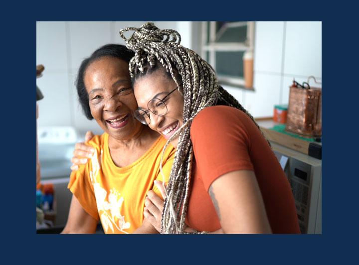 portrait of grandmother and granddaughter embracing at home.