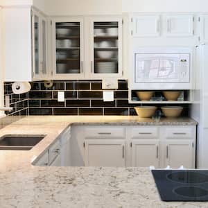 A traditional kitchen with a granite countertop and white cabinets