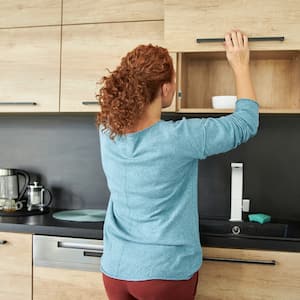 woman in kitchen opening brown cabinets