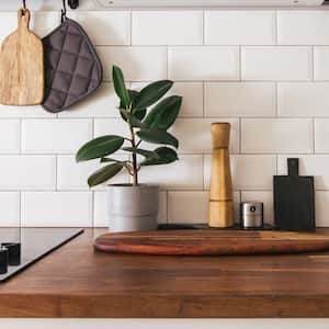 A wooden kitchen countertop with white subway tiles on the wall