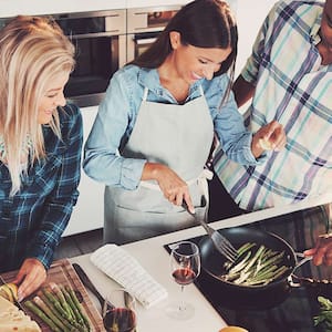 Friends laugh and cook on electric stovetop