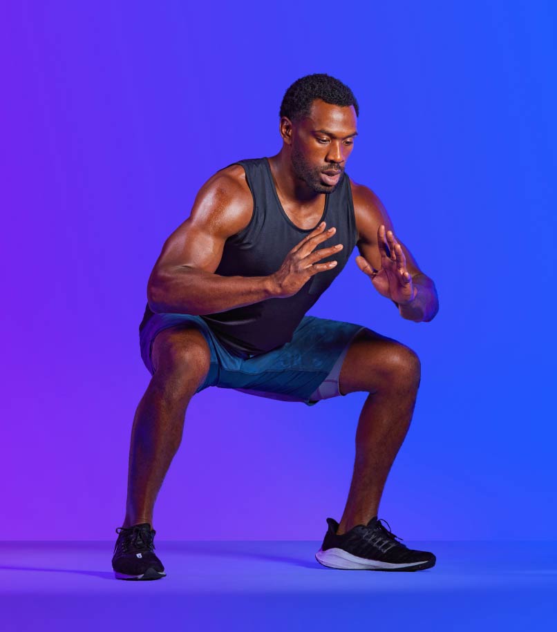 A man in workout clothes performs a squat.