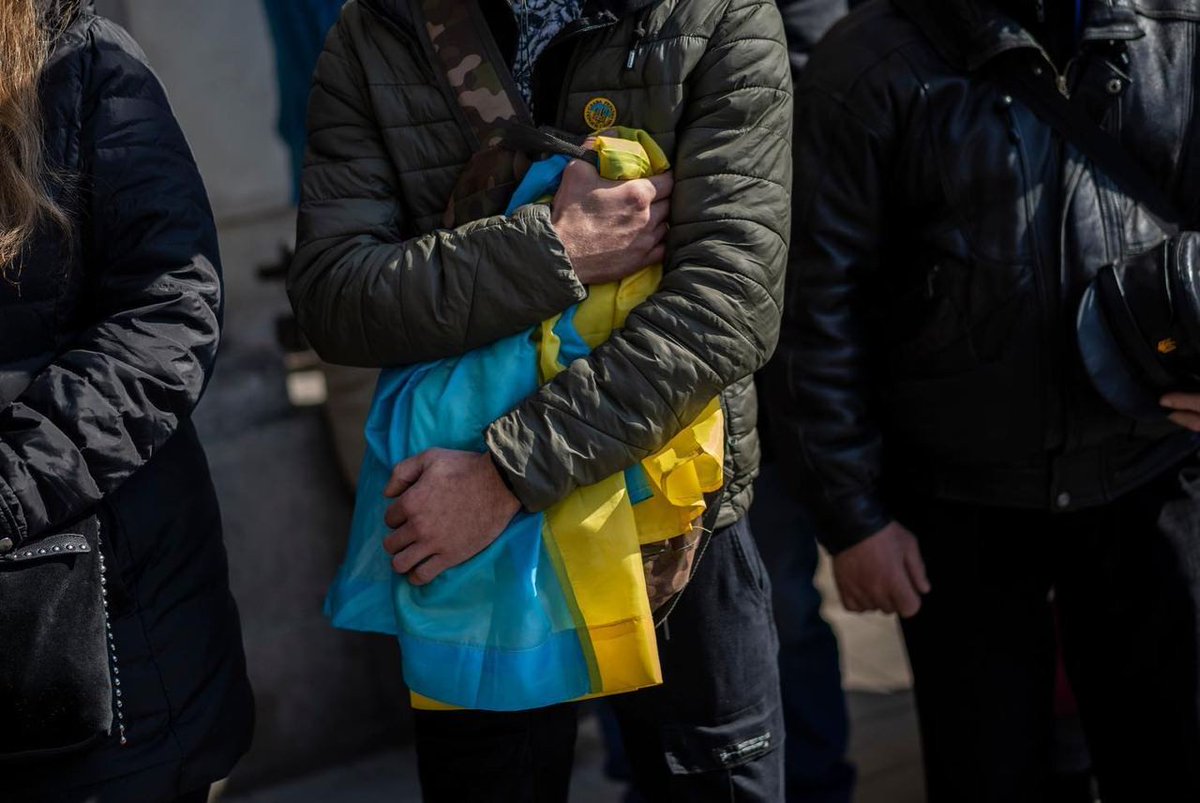 Person holding a flag of Ukraine in its arms 