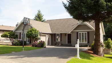 suburban house with basketball hoop in driveway