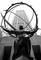 Statue of Atlas with hollow globe on his shoulders and a skyscraper in the background