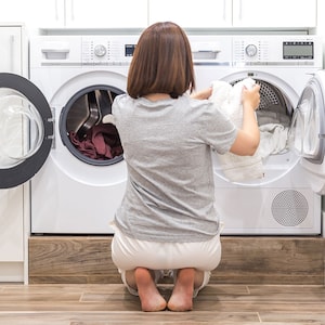 Woman crouching is loading washing machine