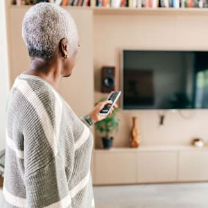 woman with short gray hair turning on TV