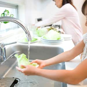  girl helping mom washing lettuce in the kitchen